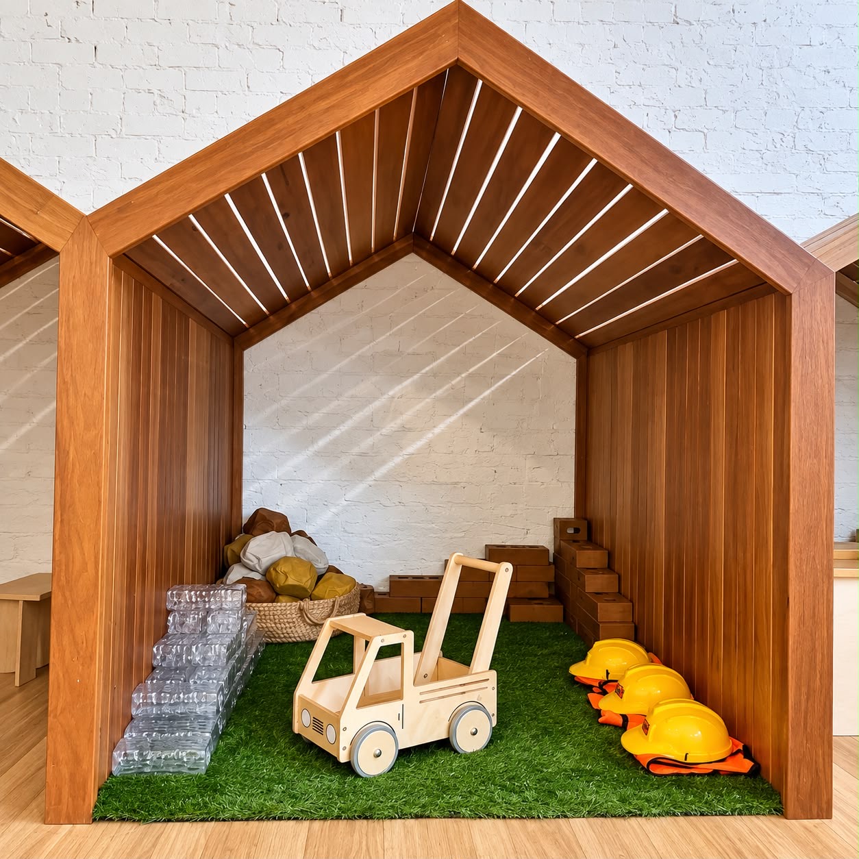 A timber construction cubby with a toy forklift, blocks and yellow hard hats