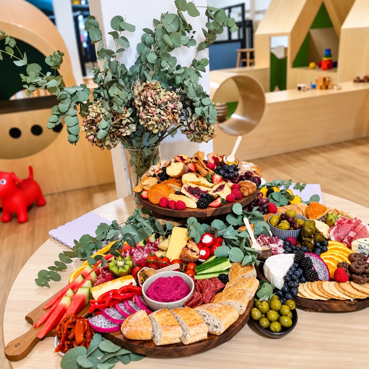 Grazing platters with fruit, cheeses, bread and dips beside eucalyptus flowers