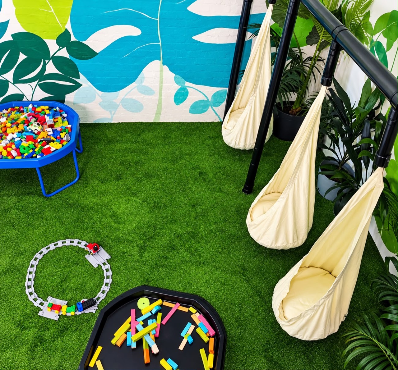 Cream pod swings beside trays of building blocks and a toy train track