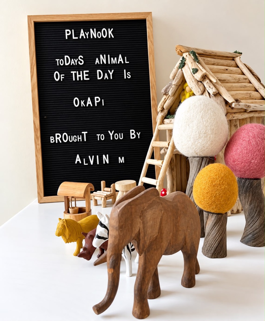 Wooden animal figures and felt trees beside Play Nook's animal of the day board